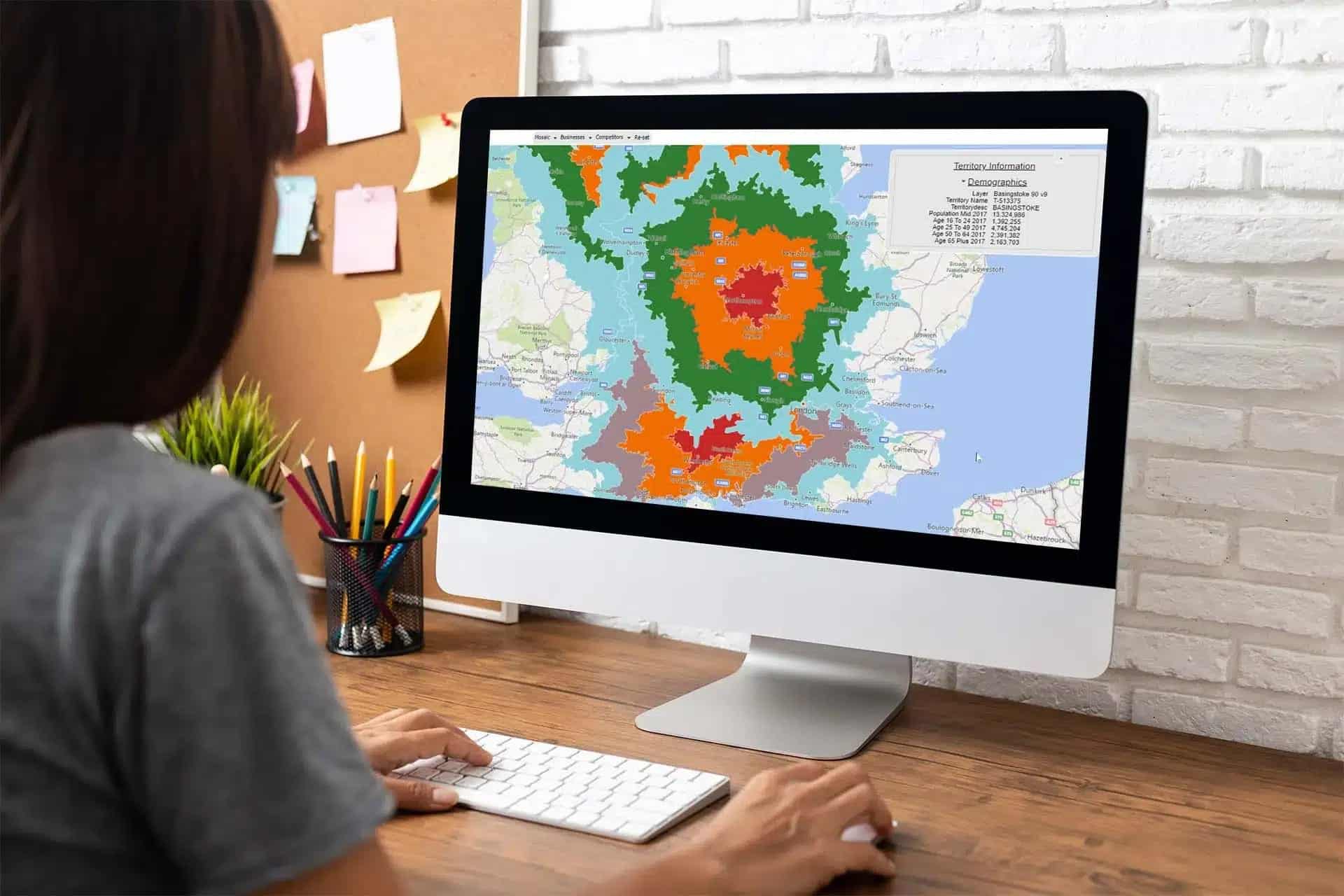 An Apple mac computer with a very bright territory map, in a circular shape with green, orange and red at the centre to show the benefits of franchise mapping for businesses.